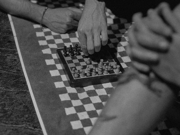 Close-up of a chess game with pieces on a checkered board - — Ilford Delta 400 film emulation preset by PresetVault