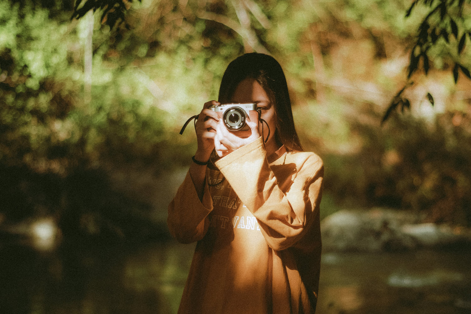 Person holding a camera in a forest setting - Agfa Optima film emulation preset by PresetVault